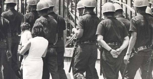 Mulher caminha entre guardas 